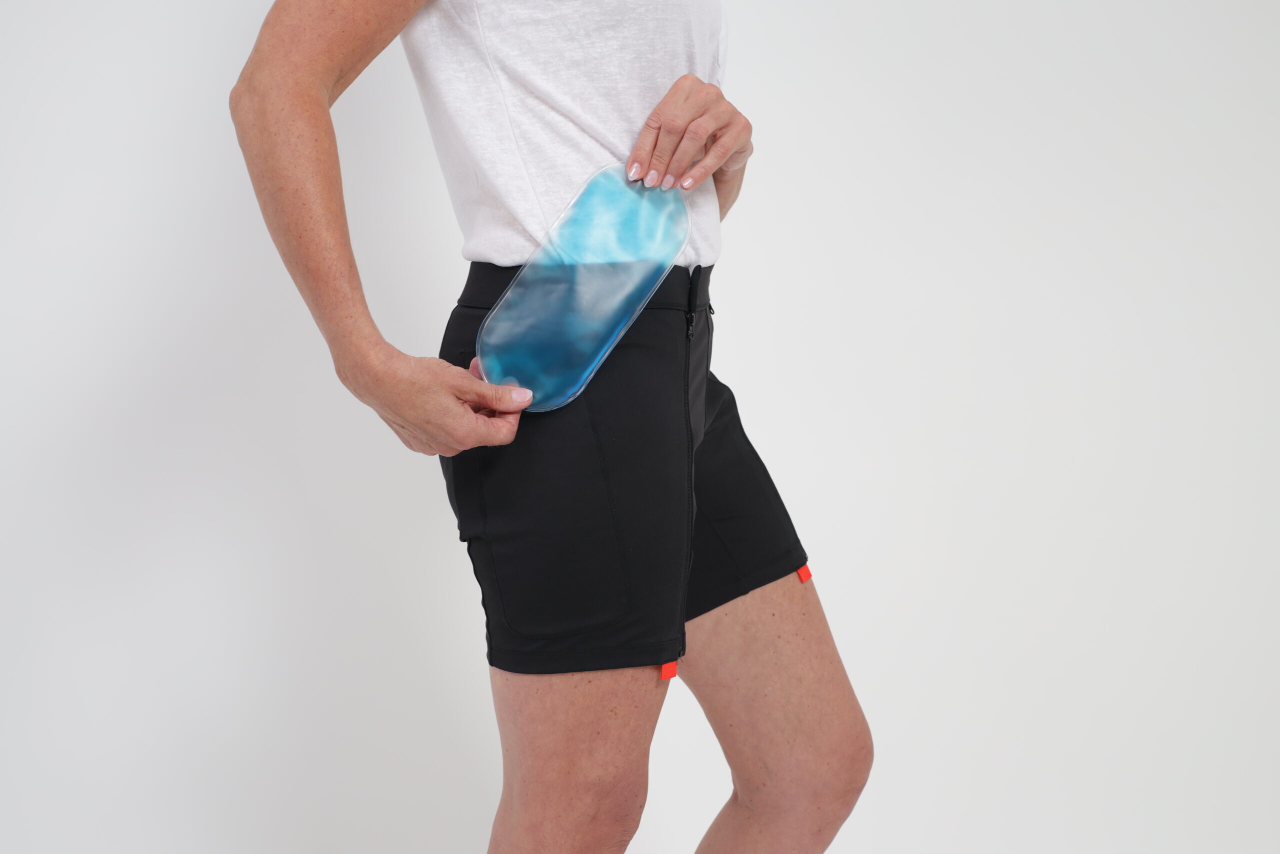 An individual demonstrates how to place an EasyReach cooling gel pad for the body into a custom pocket on the side of the shorts.